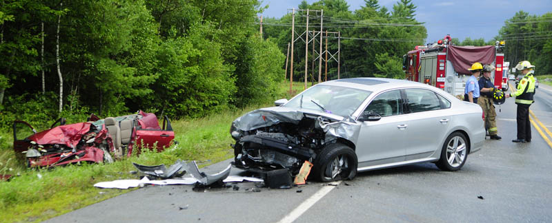 Augusta firefighters confer before leaving the scene of an accident today on the Route 3 connector, between Riverside Drive and North Belfast Avenue, in Augusta. The roof of the red car at left was cut off by firefighters during their extrication of passengers. There was a third vehicle in the collision.