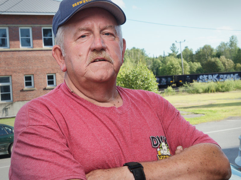 Richard Monahan, 63, stands outside the American Legion Hall at Brownville Junction after cooking a meatloaf dinner for town seniors last Tuesday. Behind him is an empty two-story building that once served as the railroad station for the Canadian Pacific Railway Co. Until 1994, the railroad operated trains between Montreal and Saint John, New Brunswick. Monahan said the railroad offered passenger service between the two Canadian cities through Maine, and he once rode the train to Montreal.