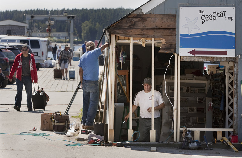 Tim Harris and Joseph Richardi of Port Clyde repair damage last week to a shop damaged in the fatal crash at the wharf in Port Clyde.