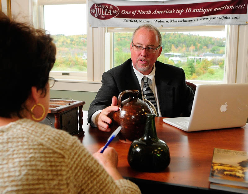 Martin Willis, James A. Julia Inc.'s director of decorative arts for the greater Boston area, points out a thumbprint in a red ware jug that Jane Paxton, of Hallowell, left, brought in for an appraisal today at the Cohen Center in Hallowell. The antiques appraisal event was a fundraiser for a group working to preserve the Hallowell fire station.