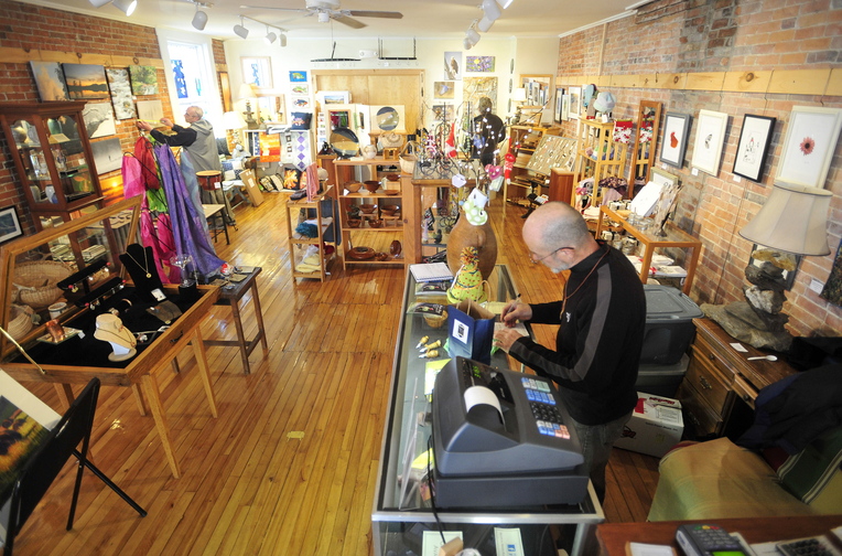 Shopping small: James Albert writes out a receipt for a shopper Saturday at River Roads Artisans Gallery on Water Street in downtown Skowhegan. Small Business Saturday kicked off the weekend following a big Black Friday.