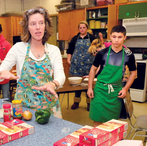 THE BASICS: Skowhegan Area High School teacher Beth Scherpf speaks with students in the Basic Foods class last month. At right, student Jeremy Silva prepares to make pizza pockets.