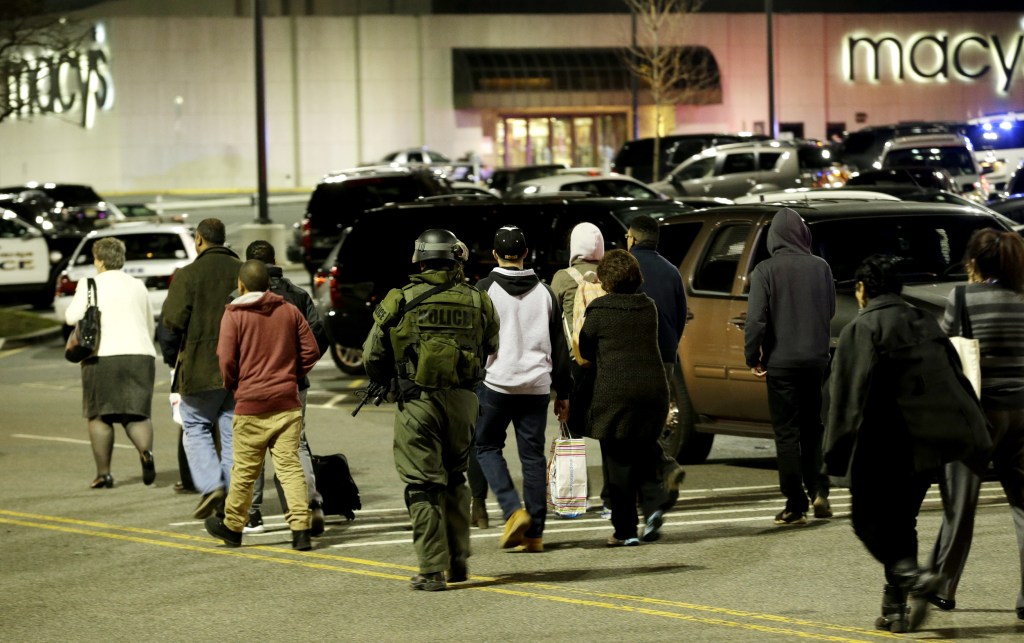 An official wearing tactical gear leads a group of people out of the Garden State Plaza Mall during a lockdown following reports of a shooter, Tuesday in Paramus, N.J.