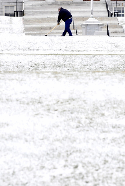 Staff photo by David Leaming HERE WE GO AGAIN: Colby College employee Earl Michaud shovels snow from the sidewalk in front of Miller Library in Waterville on Tuesday. Michaud rolled his eyes at the thought of the long winter and work ahead.