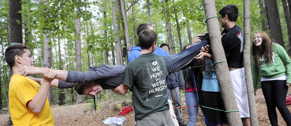 HELPING HANDS: Cony High School student Noah Guerrette is carried through ropes on the spider pull earlier this year at the school’s rope course in Augusta. The physical education class emphasizes cooperation instead of competition.