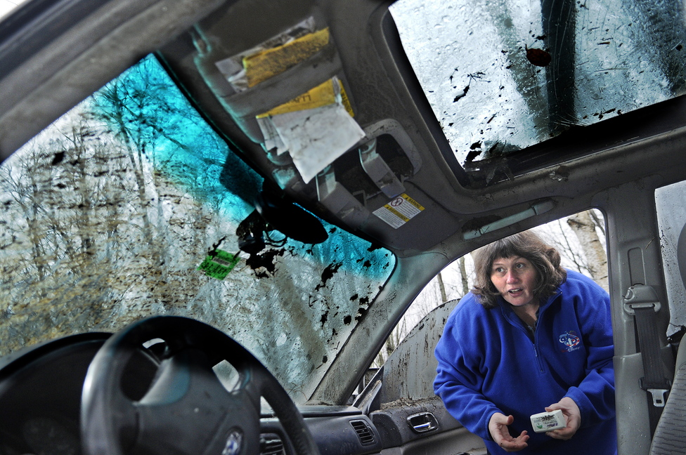 RESCUE: Becky Berlew removes items from her car Monday at her Pittston home after the vehicle rolled off the road into a water-filled ditch. Berlew credits Kennebec Journal carrier Troy Rundstrom, of Dresden, with rescuing her as the car filled with water during an early morning accident in Dresden.