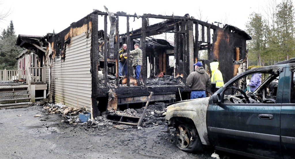 SALVAGE: Inside the burned ruins of his home, Ben Martin, right, and his friend Andy Pomeroy look for salvageable items after fire destroyed the home off U.S. Route 2 in Palmyra early Monday. Pomeroy, who was staying in the home temporarily with his family, said he was awoken by the fire and helped get the five adults and four children out. He said he lost his pregnant dog, Carly, in the fire.