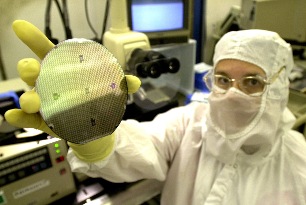 A Fairchild fabricator inspects a wafer at the plant in South Portland. Semiconductor manufacturers do a lot of business in Asia and should benefit from the elimination of tariffs.