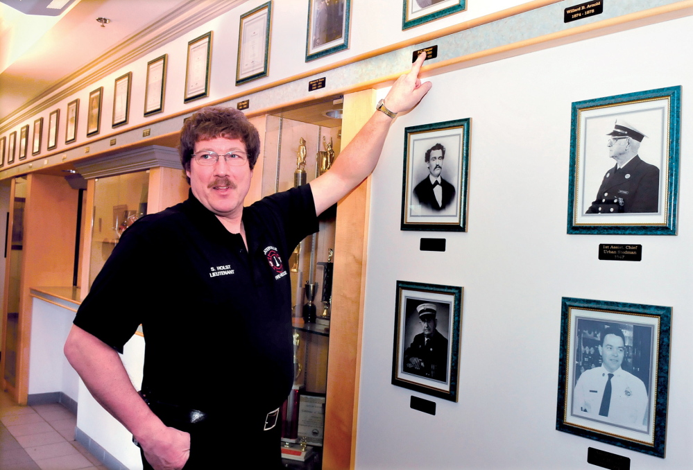 HISTORY BUFF: Waterville Fire Department Lt. Scott Holst speaks beside a wall of photographs of former fire chiefs recently. Holst is updating and expanding on a book documenting the history of the department.