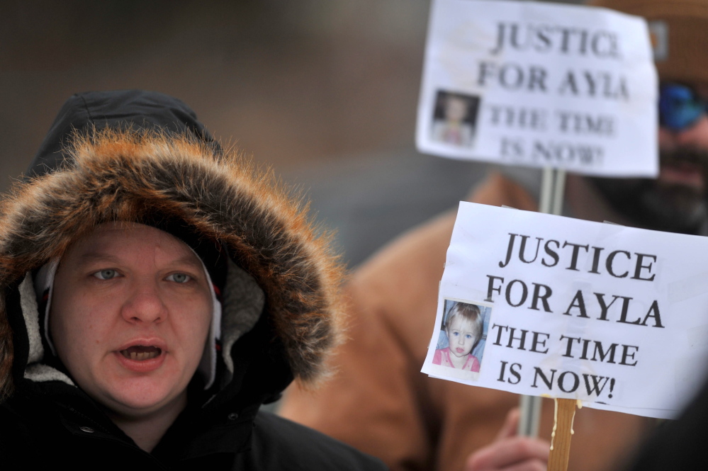 awareness: Ann Carrillo, 37, of Waterville, holds a sign Saturday during a demonstration to raise awareness about the open missing-toddler case at the Waterville police station.
