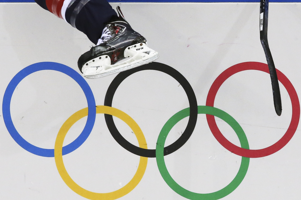 A USA women’s ice hockey player jumps over the boards and into bench during the third period against Finland at the 2014 Winter Olympics.