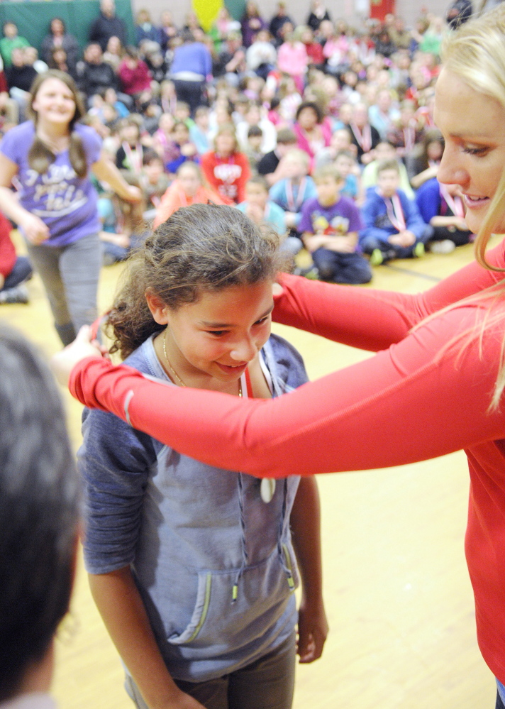 ACHIEVEMENT: Jasmine Daley, left, gets a medal from Olympic luger Julia Clukey during a medal ceremony for academic test scores on Thursday at Farrington School in Augusta.