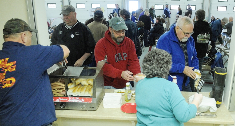 Light Lunch: Ernie Pierce, left, and Joan Mank, serve up hot dogs before the start of the 163rd West Gardiner Town Meeting on Saturday at the West Gardiner Fire Station. The dogs, sodas and treats were free, but there was a boot, at right, if anybody wanted to make a donation to the fire department.