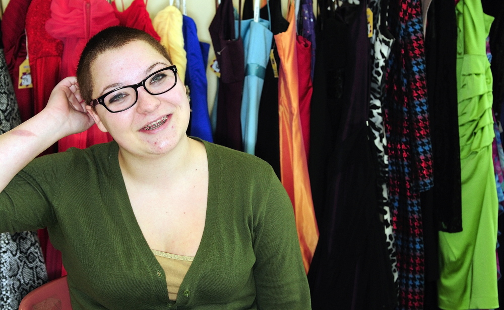 Hayley Corson sits in front of some of the donated dresses seen last week at Gardiner Area High School. Corson had her head shaved earlier this year for cancer fundraiser.