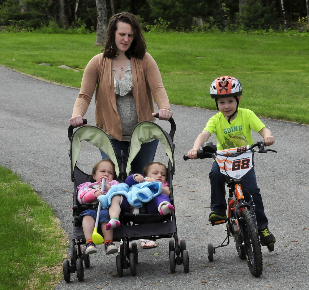 REBOUNDING: Emily Walker takes her children out for some fresh air at an undisclosed location on Tuesday. Her twin 2-year-old daughters Maddilyn, left, and Brooklyn are in the stroller and suffered broken bone injuries on May 11. Their brother Wyatt tags along on his bike. Walker says her former boyfriend David Devine, who has been charged with the assault, never showed signs of violence.