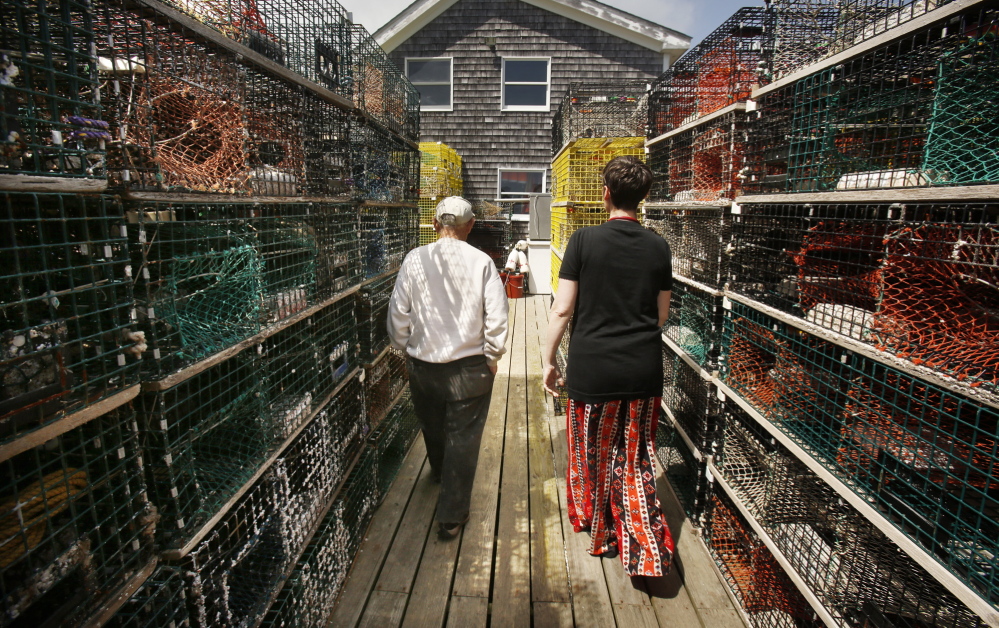 Jennifer Desmond walks past lobster traps with Harold âSonnyâ Warren on the dock at his Vinalhaven home last month. Desmond has a recreational lobster license and Warren, who is also a Korean War veteran, helps her haul her traps. âHeâs my sternman,â she said.