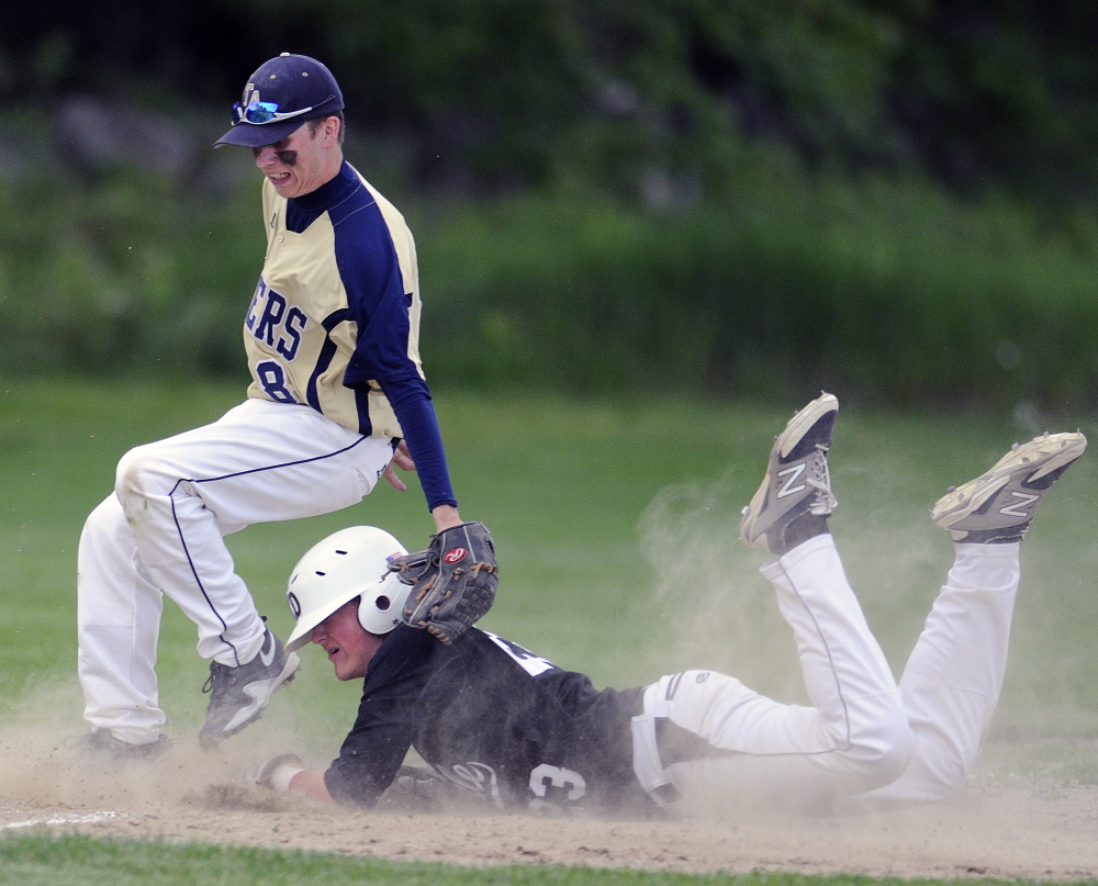 Staff photo by Andy Molloy SAFE: Hall-Dale High School’s Ryan Sinclair slides under the tag of Traip Academy’s Joe Spinney at third base Tuesday in Farmingdale.