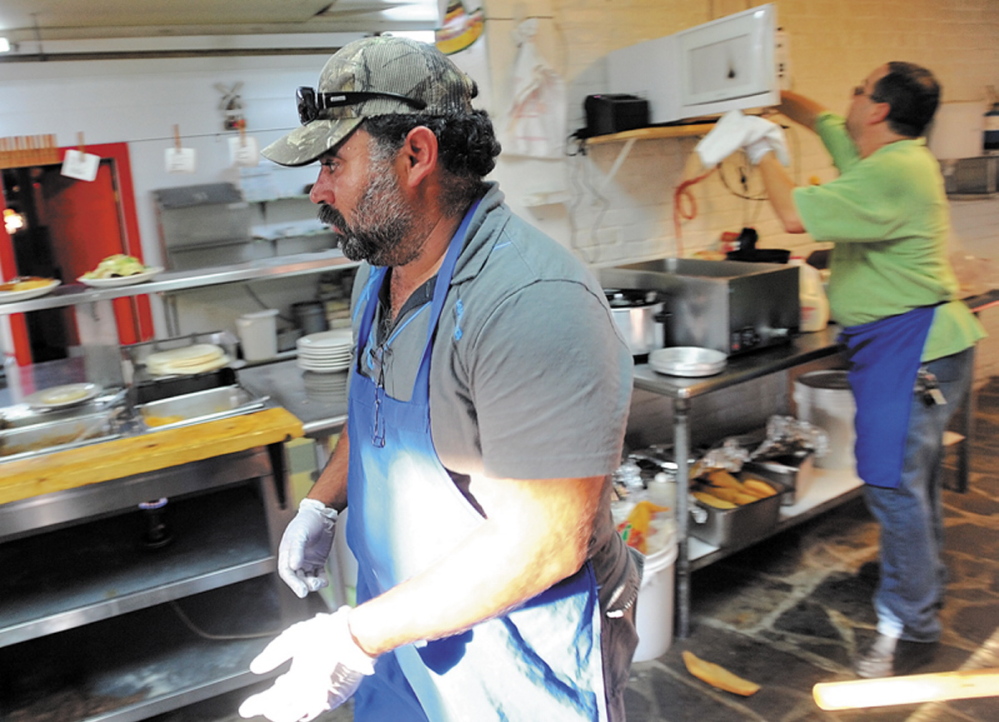 WORKING HARD: Myao Perez, center, hustles in the kitchen at Cancun Restaurant in Waterville as Hector Fuentes, back right prepares food for the dinner rush Tuesday.
WORKING HARD: Myao Perez, center, hustles in the kitchen at Cancun Restaurant in Waterville as Hector Fuentes, back right prepares food for the dinner rush Tuesday. Perez is one of many friends of Fuentes who has volunteered his time to help his friend keep his business open after several workers were arrested for charges of illegal immigration.