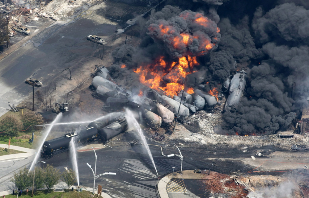 This July 6, 2013, file photo shows smoke rising from railway cars that were carrying crude oil after derailing in downtown Lac-Megantic, Quebec. The July 6, 2013, explosion and fire occurred when a runaway train carrying 72 carloads of crude oil derailed, hurtled down an incline and slammed into downtown Lac-Megantic. Some 40 buildings were leveled and 47 people were killed.