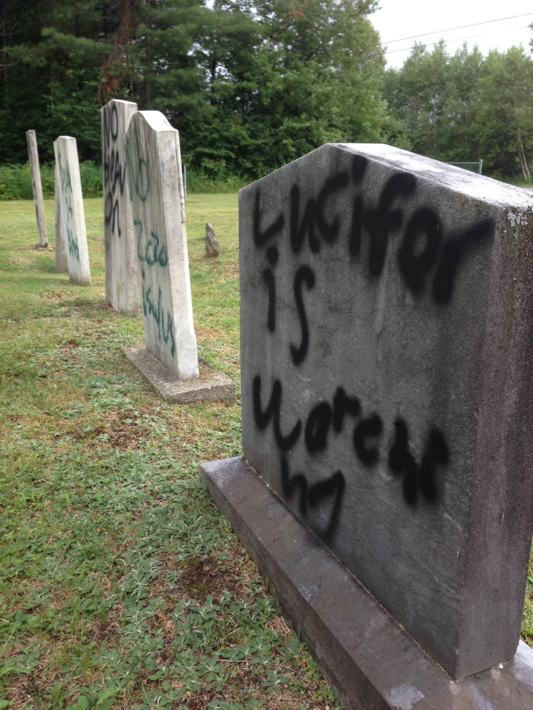 “Lucifer is watching,” proclaims a message spray-painted on a gravestone in Pleasant View Ridge Cemetery in China on Wednesday.