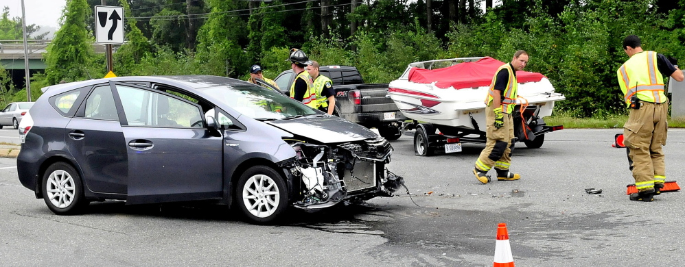 Waterville police and firefighters work around the accident scene where a car and a truck pulling a motorboat collided Tuesday on Kennedy Memorial Drive near an Interstate 95 exit ramp in Waterville.