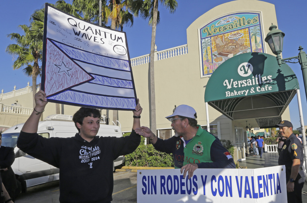 Anti-Castro protester Lazaro Lozano, right, argues with pro-Obama supporter Bryan Medina, left, in the Little Havana area of Miami, Wednesday, Dec. 17, 2014. Lozano expressed his disagreement with a surprise move announced by senior Obama administration officials that could pave the way for a major shift in U.S. policy toward the communist island nation, as Medina, who supports the move, looks on. (AP Photo/Alan Diaz)