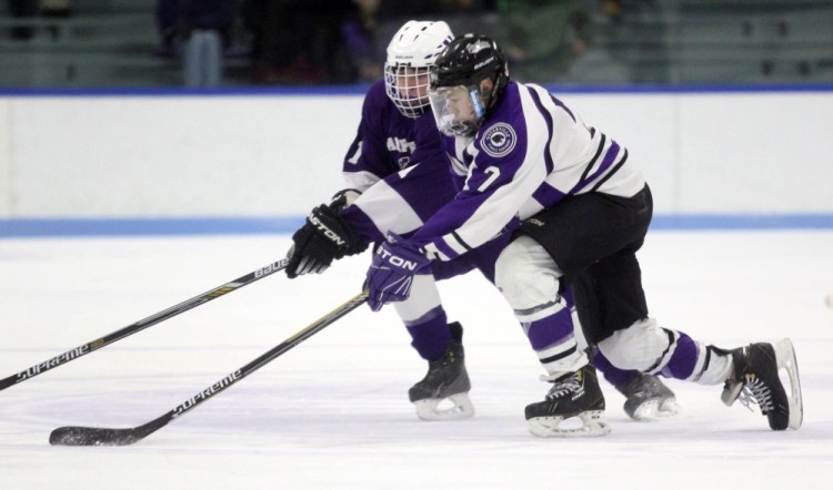 Waterville Senior High School forward Nick Denis tries to keep the puck away from Hampden Academy’s Hunter Christian during first period action of an Eastern B game Thursday in Waterville.