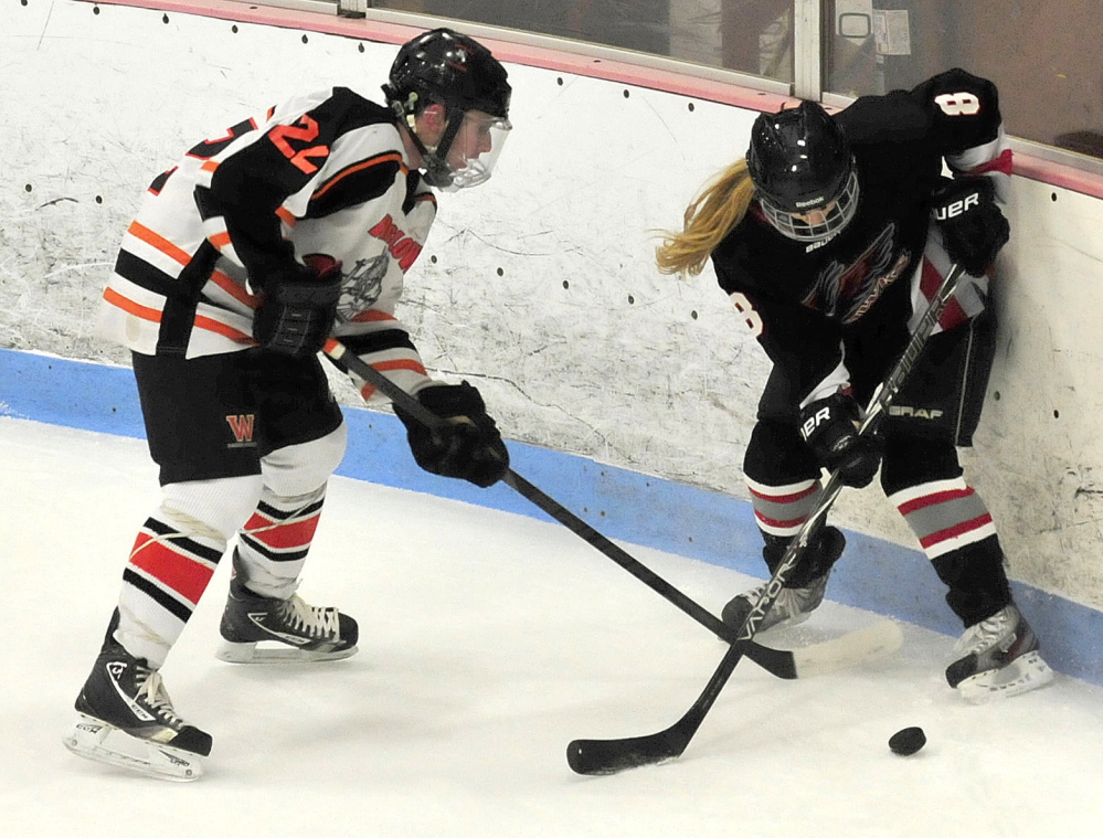 Winslow’s Dameron Rodrigue and Maranacook’s Nicole MacMillan go after puck during game Wednesday at Sukee Arena in Winslow.