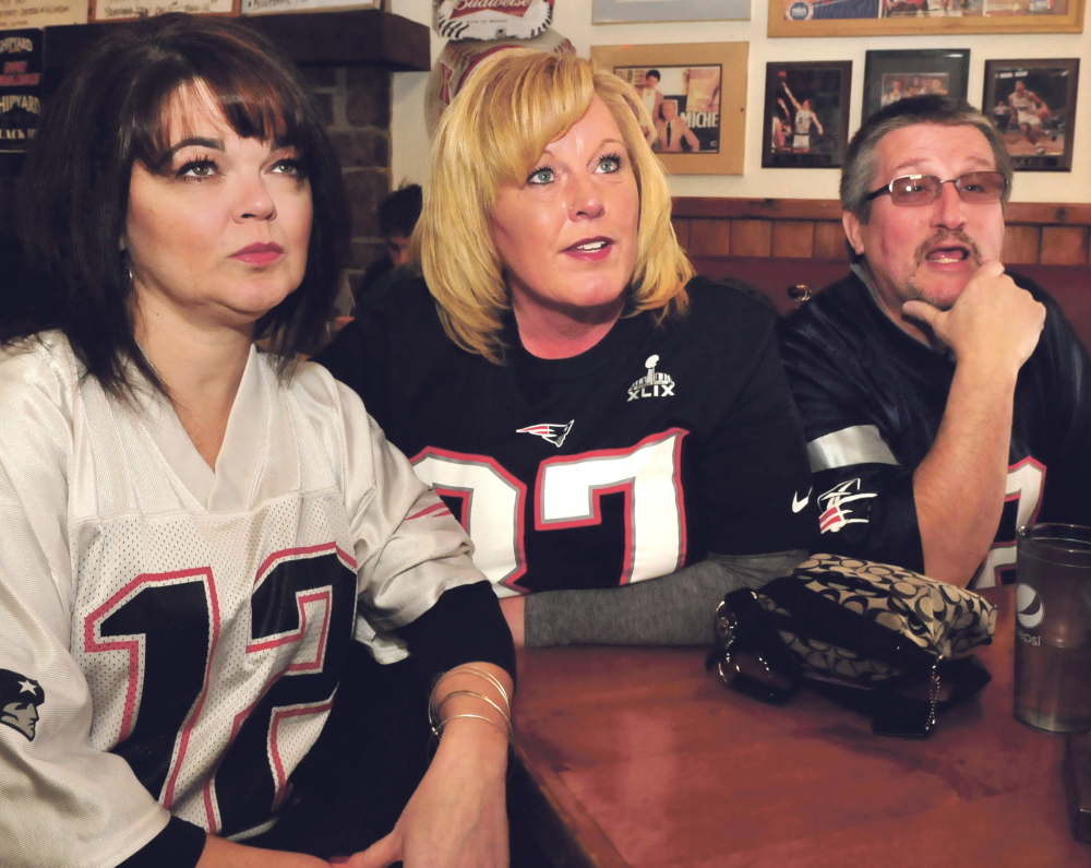 New England Patriots football fans gather at the Pointe Afta restaurant Sunday in Winslow to cheer their team on against the defending champion Seattle Seahawks in the Super Bowl. Cathy LeClair, left, and Tammy and Steve Denis all said they support the Patriots, and Tammy Denis added she loves getting together with other New England fans.