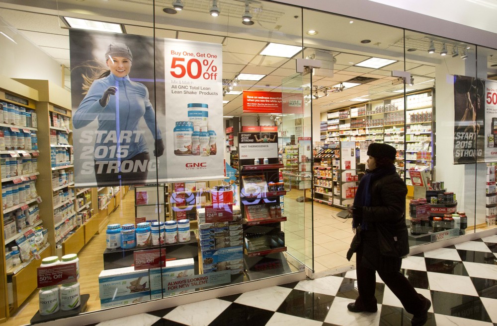 A woman walks past a GNC store Tuesday in New York. Numerous store brand supplements aren’t what their labels claim to be, an ongoing investigation of popular herbal supplements has found.