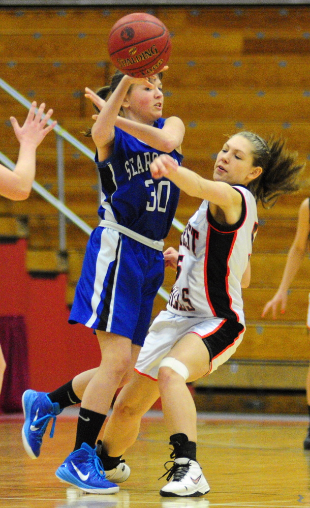 Searsport sophomore guard Paige Ireland, left, passes under defensive pressure from Forest Hills senior guard Samantha Begin during a Western D quarterfinal game Tuesday at the Augusta Civic Center.