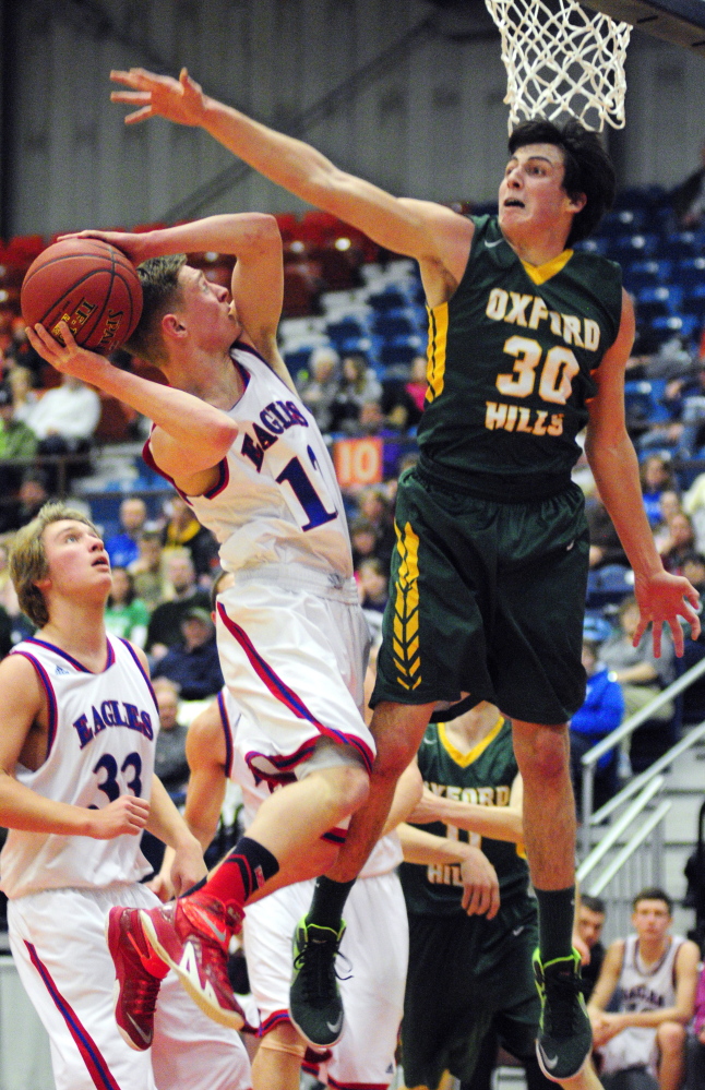 Messalonskee senior guard Trevor Gettig, left, shoots as Oxford Hills senior forward Patrick Marco defends during an Eastern A quarterfinal game Saturday at the Augusta Civic Center.