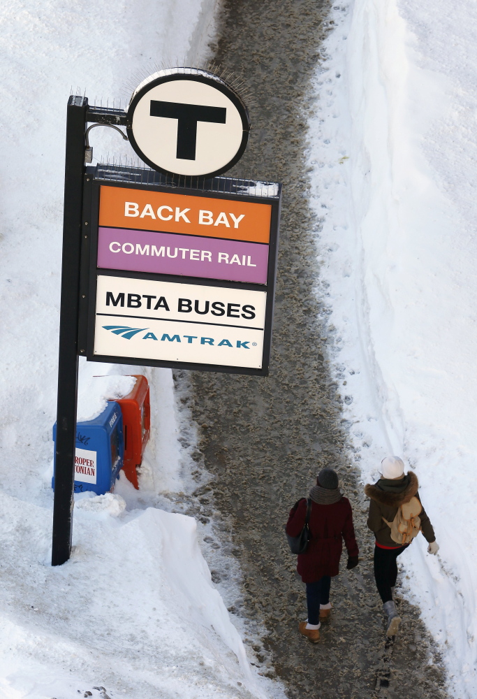 Pedestrians walk on a cleared sidewalk outside Back Bay Station in Boston on Monday.