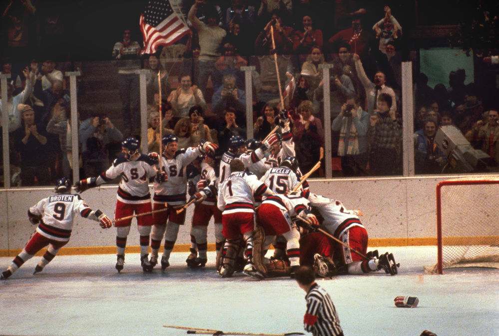 The U.S. hockey team pounces on goalie Jim Craig after a 4-3 victory against the Soviets in the 1980 Olympics, as a flag waves from the partisan Lake Placid, N.Y., crowd.