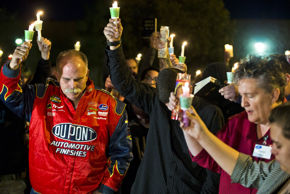 Robert Meyers, left, and others bow their heads during a prayer at a candlelight vigil Tuesday for his wife, Tammy, who was taken off life support on Saturday after a shooting in Las Vegas.