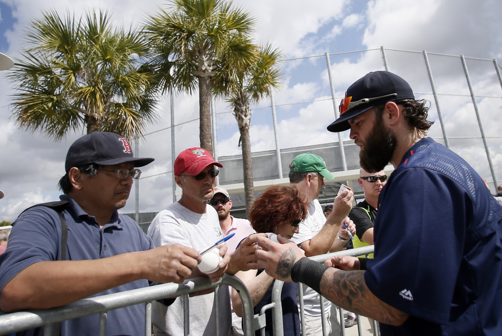 Boston Red Sox first baseman Mike Napoli, right, signs autographs for fans after a workout Monday at spring training in Fort Myers, Fla.