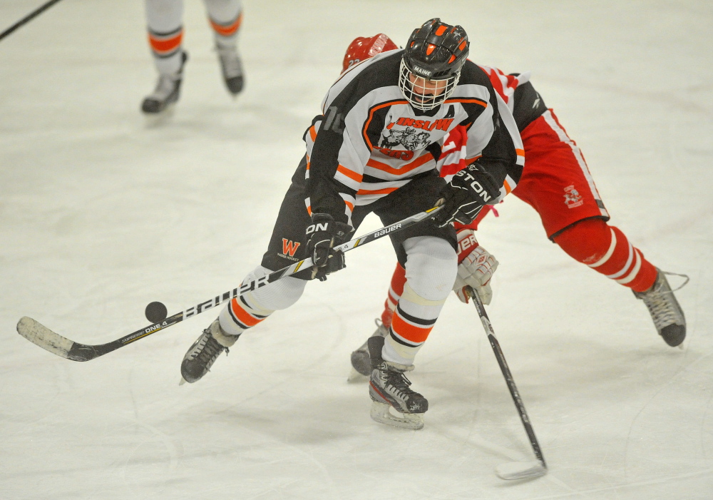 Winslow High School’s Jacob Trask, front, battles for the puck with Cony’s Spencer Buck during a game last month. The Raiders open the Eastern B playoffs Tuesday night against Hampden.