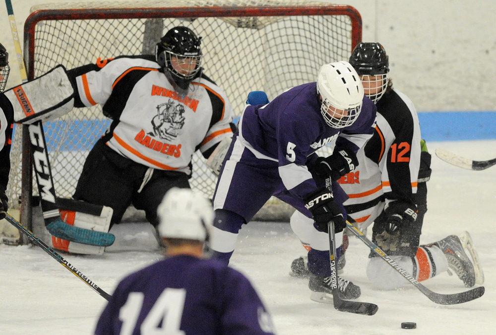 Winslow’s Jake Larsen (12) defends Hampden’s Jordan Dysart (5) as goalie Andrew Beals defends.