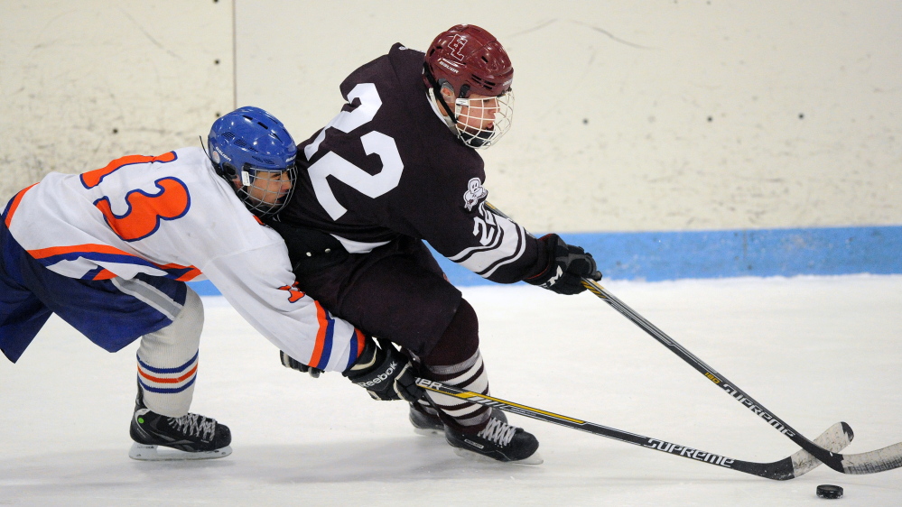 Staff photo by Michael G. Seamans 
 Lawrence/Skowhegan Samuel Haver (13) battles for the puck with Edward Little's Cade Chapman (22) during an Eastern A quarterfinal Tuesday night at Sukee Arena.