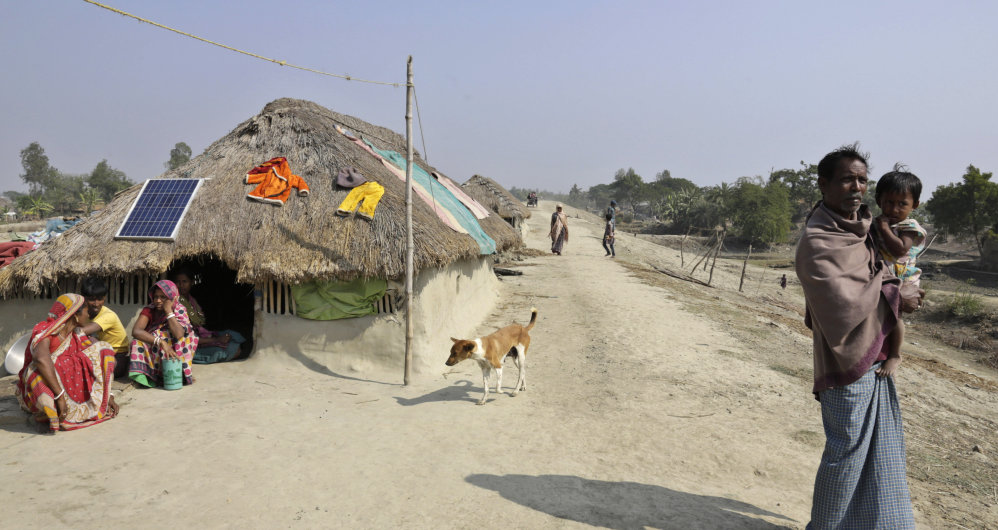 Bakul Mondal, 50, holds his granddaughter near their family home – the fifth he’s built in five years – atop a crude, mud embankment in the Sundarbans, India.