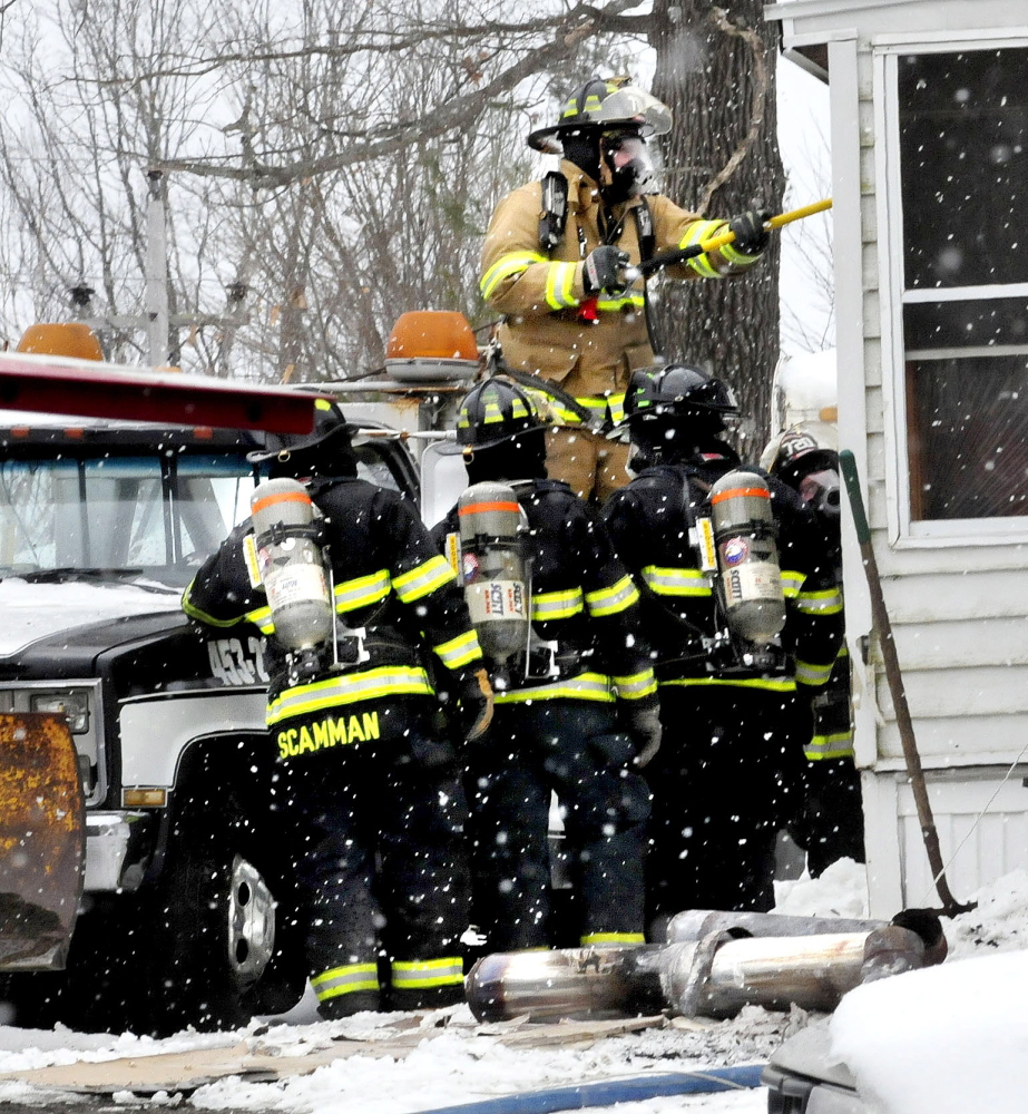 Firefighters use tools to open up walls and roof to get to fire that did serious damage to a home on Crummett Street in Benton on Tuesday. Firefighters tore off sections of metal chimney section on ground.