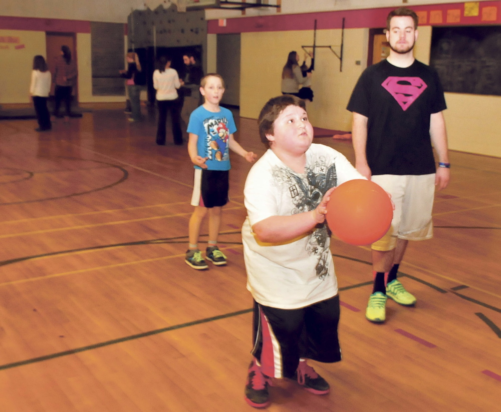 Messalonskee High School student Connor Garland watches as Jarod Jones tries a shot while playing games during a Big Brothers Big Sisters organization gathering Wednesday at Williams Elementary School. Awaiting his turn is Brandon Violette. Garland was injured in the hayride accident that killed Cassidy Charette in October. Wednesday’s event was held in her honor.