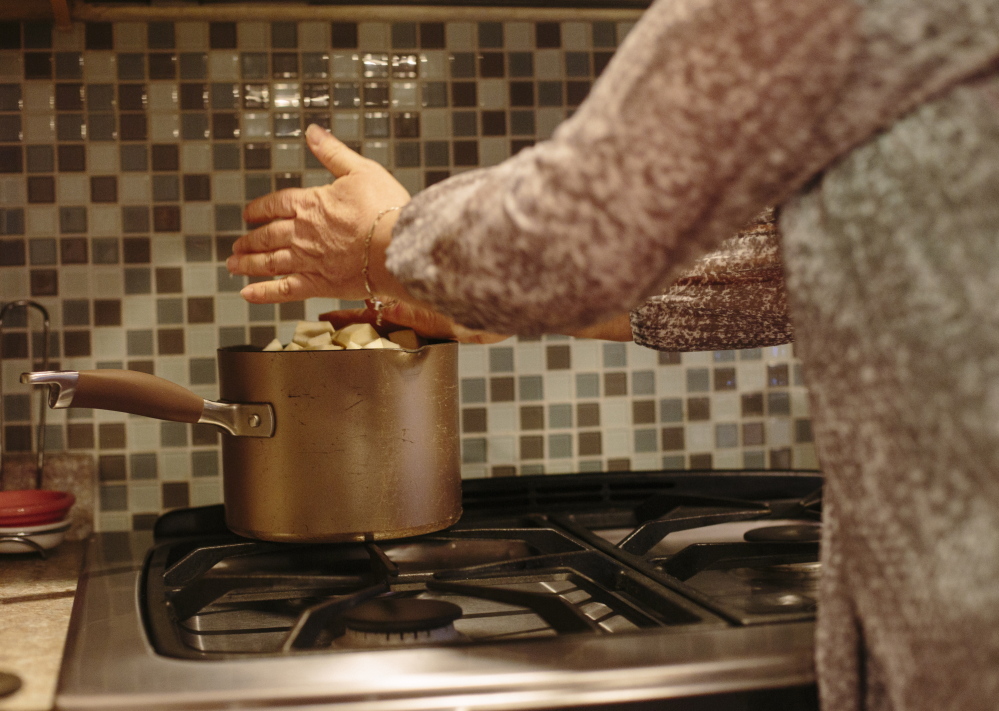 Julie Johnson places chopped turnip into a pot for a mashed vegetable dish and, below, slices a red pepper. Johnson says she was a “person who rolled my eyes at vegetarians” until she was convinced by the documentary “Forks Over Knives” to change her diet.