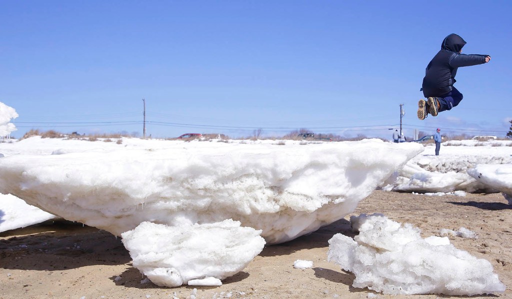 Cylus Kellereher, 7, of Portsmouth, N.H., jumps off a huge chunk of ice onto the beach in Wellfleet, Mass., on Thursday. The Associated Press