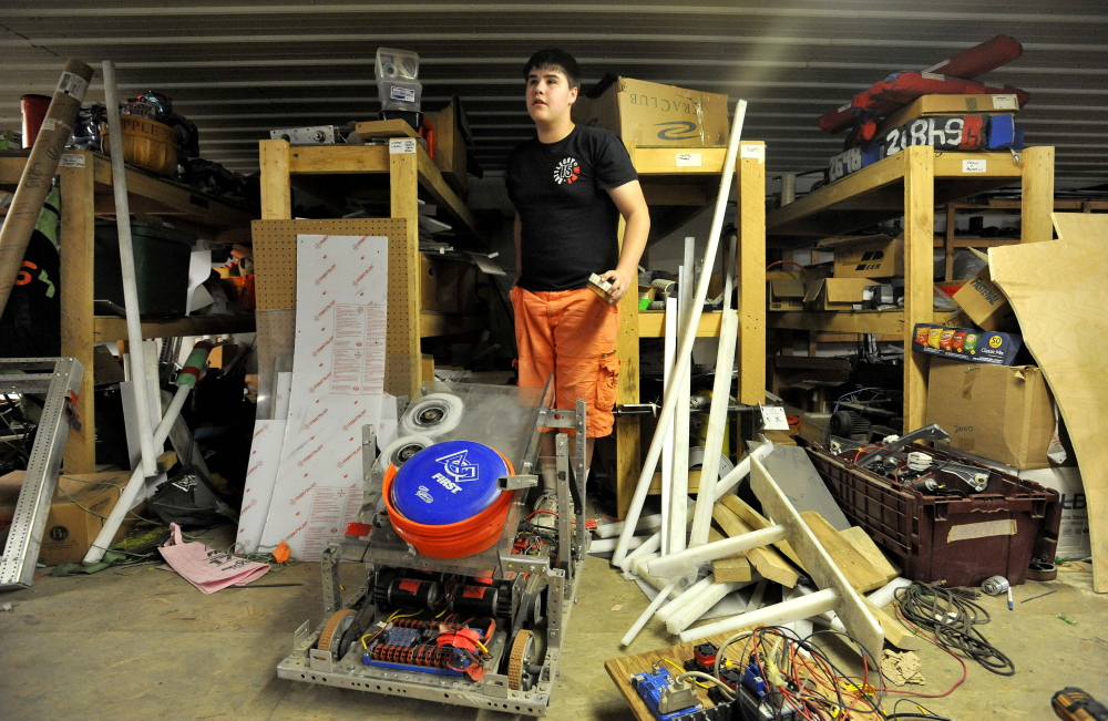 Delsin Klein, 14, emerges from shelves of parts as he works on the Messalonskee robotics team robot on Thursday at Wrabacon in Oakland.