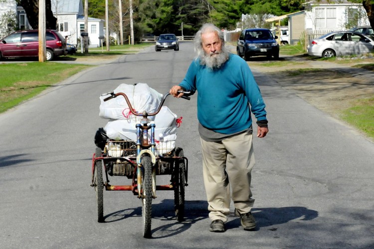 Neil Woodard wheels his bike loaded with a basket full of returnable cans and bottles he collected off Skowhegan streets and from residents on Sunday. Woodard has collected the items daily for years.