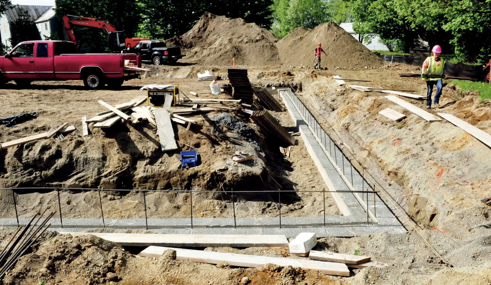 Jacob Luce, left, and Emily Basford, of Roderick Construction, carry materials for walls to the foundation of what will be the Norridgewock fire station. The project is expected to be completed in late fall.