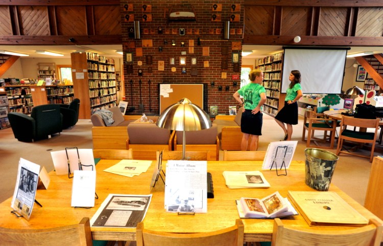 Jlynn Frazier, right, and Erica Hutchinson, center, both development officers at Unity College, prepare the library for the 50th anniversary of Unity College on Friday.