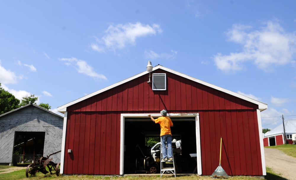 Joy Buzzell paints the door frame of the museum building on Tuesday at the Monmouth Fair grounds.