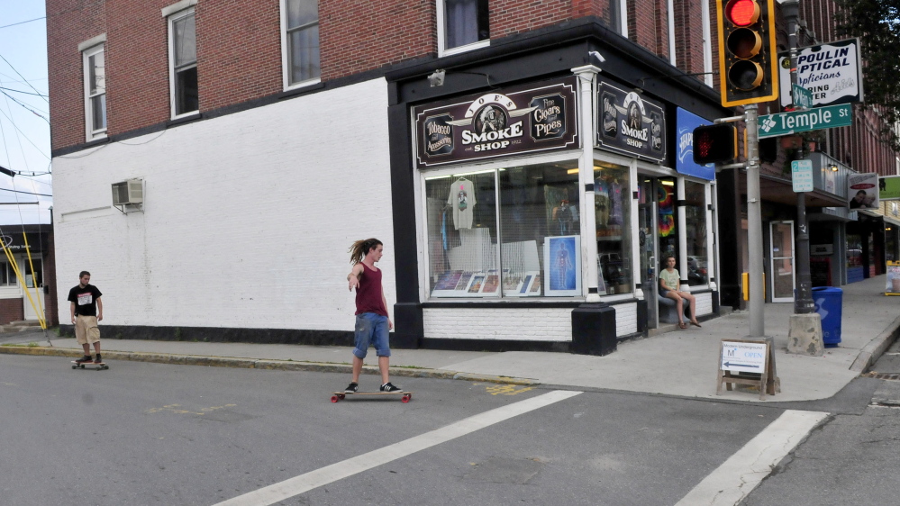 Brendan Kinsman, left, and Aidan O’Keeffe ride skateboards past Happy Trails where incoming Colby and Thomas college students abd muralist Sandra Remme paint a mural next month as part of Colby’s freshman orientation. Colby students will also create temporary parks, as well as parks on the other corners of Temple and Main Streets, Thursday.